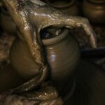 Close-up of hands shaping clay into pottery on a wheel, showcasing traditional craftsmanship.